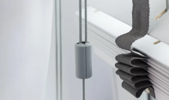 Detailaufnahme einer Jalousie mit grauem Zugseil und Stoffband