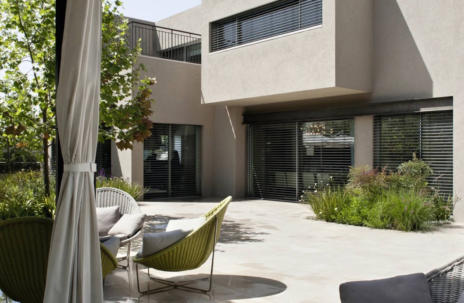 Moderne Terrasse mit stilvollen Gartenmöbeln vor einem zeitgenössischen Gebäude