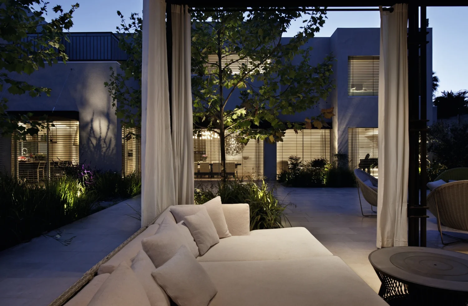 Moderne Außenansicht eines stilvollen Hauses bei Dämmerung mit gemütlichem Sofa im Vordergrund